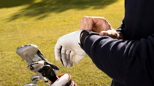 Photo man adjusting his smartwatch on the golf field