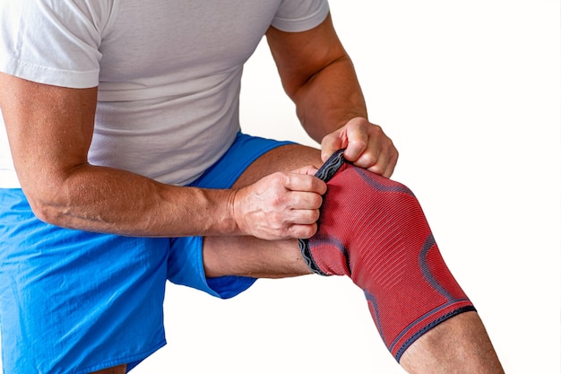 Man adjusts a compression bandage on the knee joint. Sports injury.