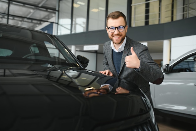 Man adult customer male buyer client wears classic suit white\
shirt chooses auto wants to buy new automobile touch check car in\
showroom vehicle salon dealership store motor show indoor sales\
concept