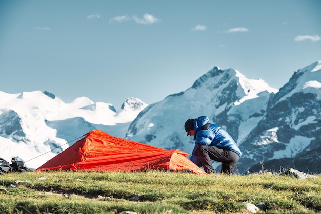 Мужчина-авантюрист ставит свою палатку в высоких горах