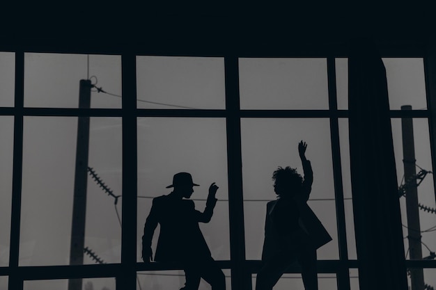 Man and african american woman with curly hair dancing on the background of the window