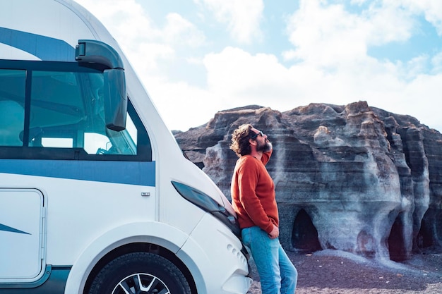 Photo man against big modern motor home camper van enjoy arrival at destination scenic place in background concept of travel and vacation in free lifestyle people and tourism with vehicle and transport