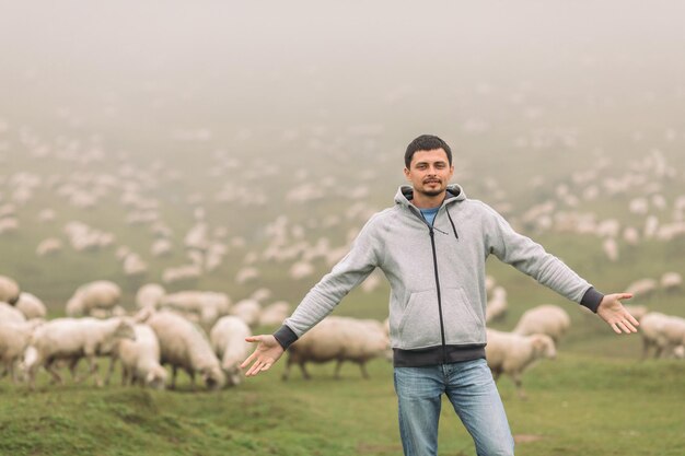 Photo man in against herds of sheep in the mountains