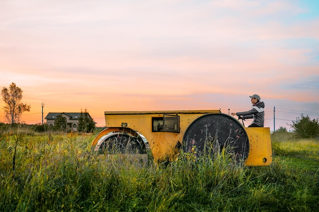 Photo man on agricultural machine at sunrise