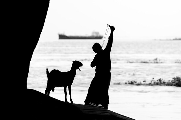 Foto un uomo che punta una tradizionale macchina da caccia agli uccelli chiamata slingshot immagine di contro la luce del sole silhouette immagine