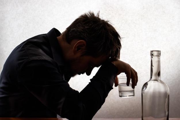 A man in alcoholic intoxication holds a glass of alcohol.