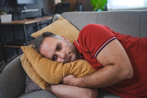 Photo man alone at home lying on sofa looking sad and distraught