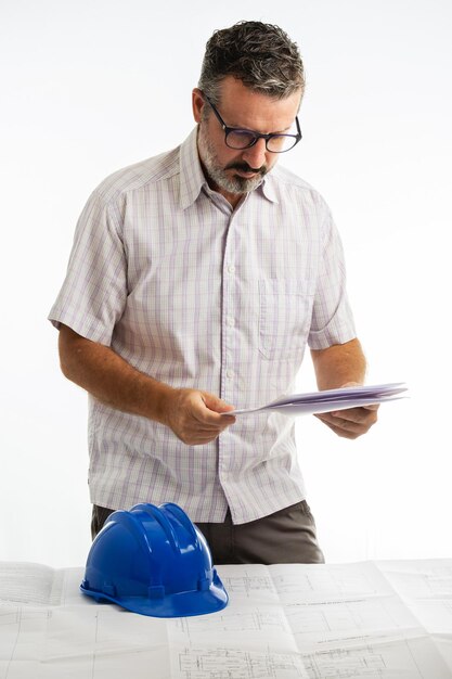 Man analyseert technisch project met zijn helm op tafel.