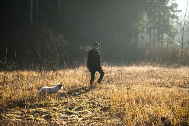 写真 人と犬が陸上の植物のそばを歩いている