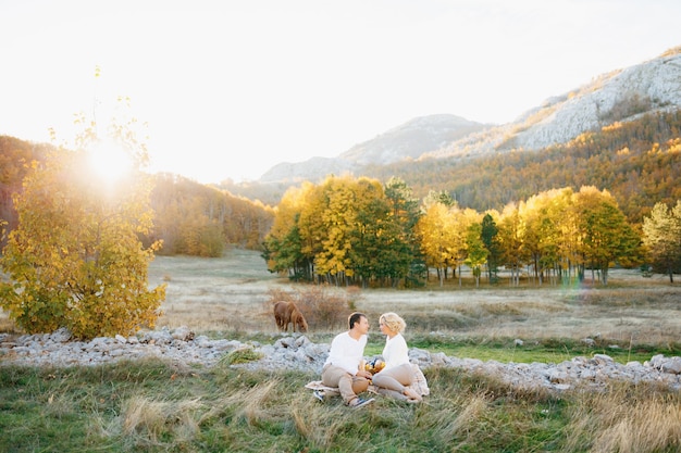 写真 男と女は秋の森の真ん中で芝生の毛布に座っています
