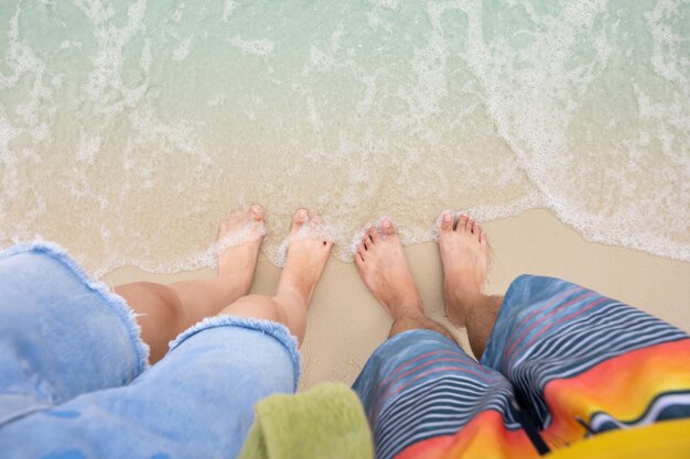 사진 남자 와 여자 의 발 은 부드러운 바다 파도 와 함께 모래 해변 에 서 있다