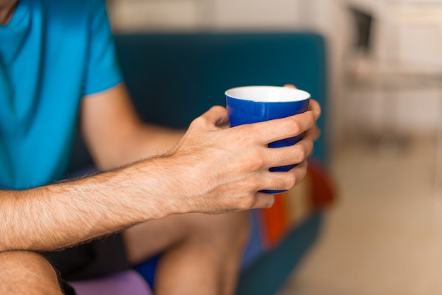 Man in an apartment holding a cup of coffee