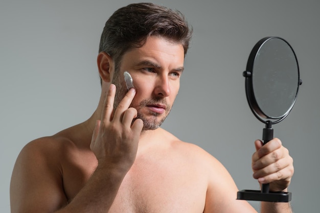 Foto uomo che applica crema per il viso routine di bellezza uomo con la pelle perfetta antiaging e crema per le rughe concetto di