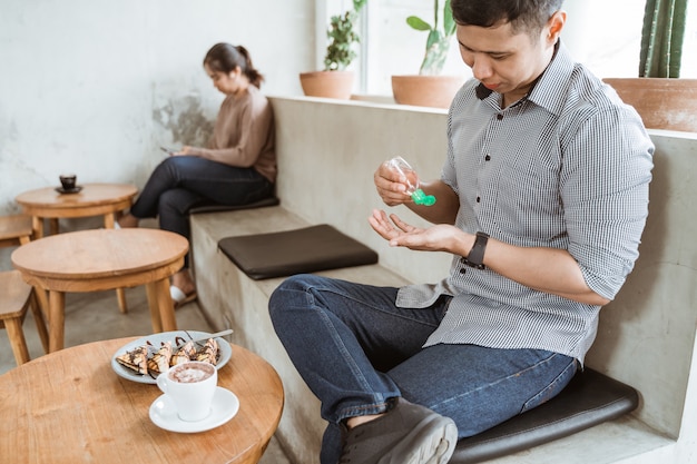 Man appying handdesinfecterend middel terwijl hij op café