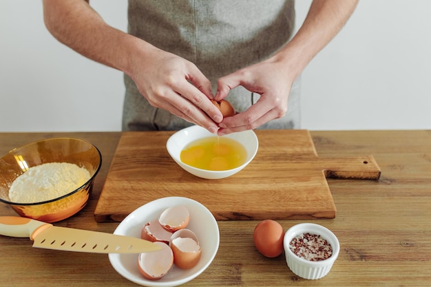 Man in apron cooking in progress Eggs flour salt on the table cutting board and knife Dough