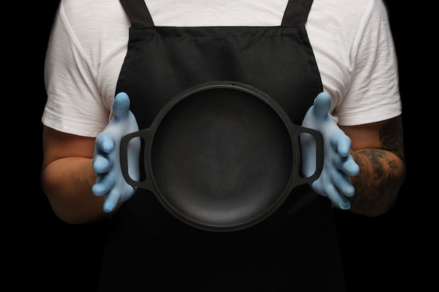 Photo a man in an apron holds an empty frying pan. mockup.