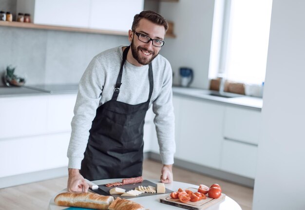 Man in an apron slicing salami for sandwiches