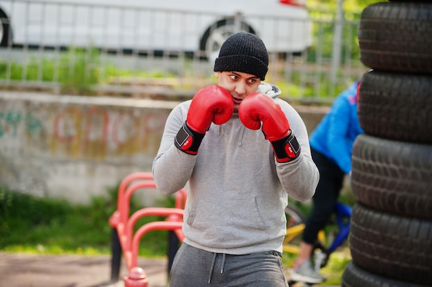 Man arabian boxer in hat training for a hard fight outdoor gym.