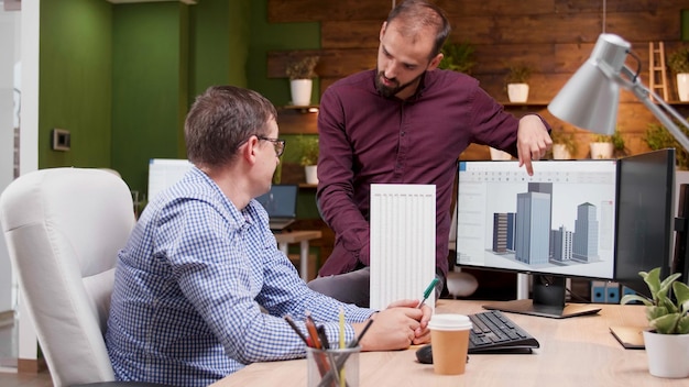 Man architect die de bouwconstructie uitlegt aan zijn ingenieurscollega die een nieuw architectonisch prototype ontwikkelt. Creativiteitsteam dat werkt in de architectuurindustrie en technische maquette plant