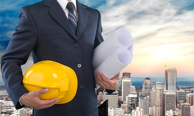 Man architect wearing suit holding blueprint and helmet.