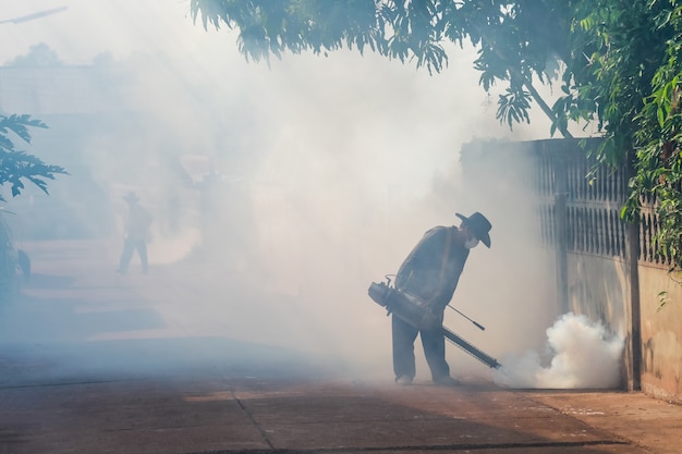 The man are spraying fumes in the village to prevent dengue fever.