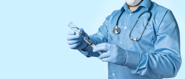 Man, arts in blauw shirt en handschoenen, met een spuit en vaccinfles in de hand tegen ziekte coronavirus of griep, vaccinatieconcept.