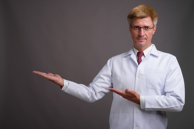 Man arts met blond haar tegen grijze muur