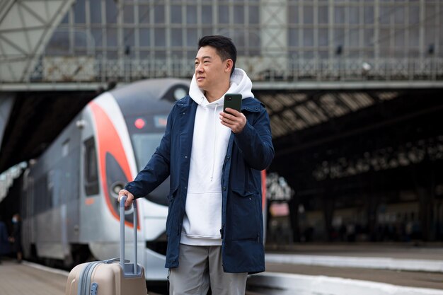 Man asian passenger arrives in nome town with big suitcase tourist at train station