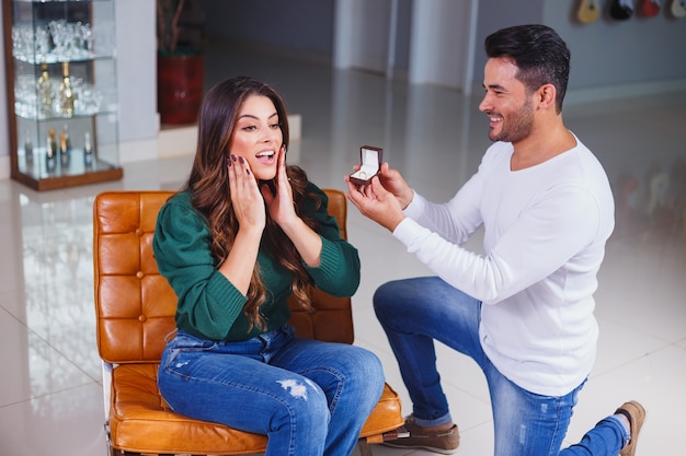 Man asking his girlfriend to marry him showing her the ring