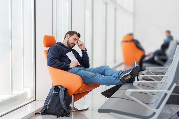 Foto uomo addormentato in una sala d'attesa stanco di aspettare il treno l'aereo il dottore la negligenza dei bagagli