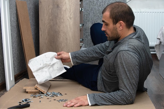 a man assembles furniture at home according to a finished drawing