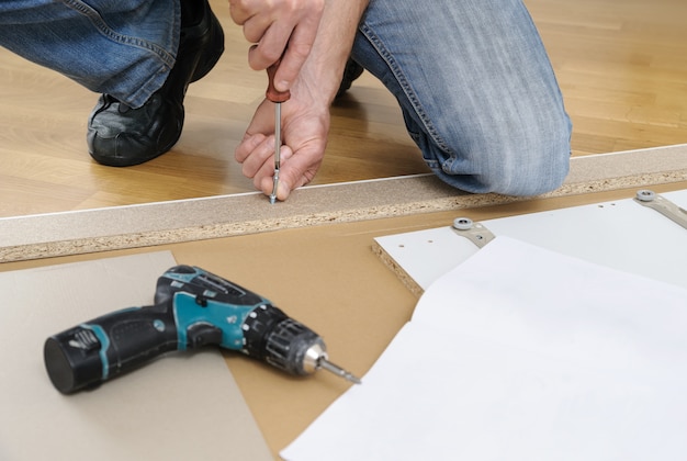 Man assembling the furniture at home  He installing Joint Connector Bolts in the furniture board