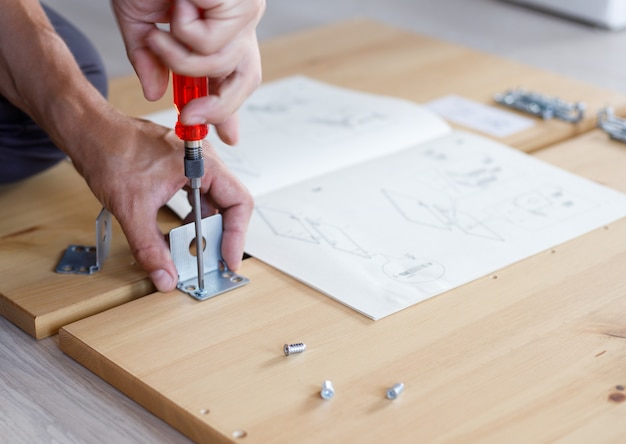 Man assembling furniture at home using screwdriver.