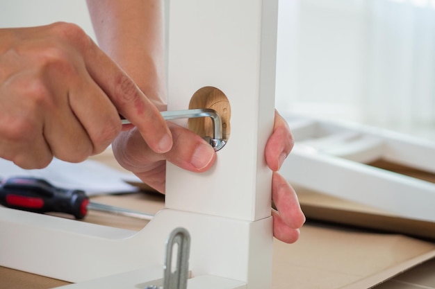 Man assembling white chair furniture at home