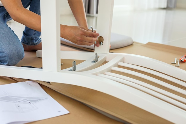 Man assembling white chair furniture at home