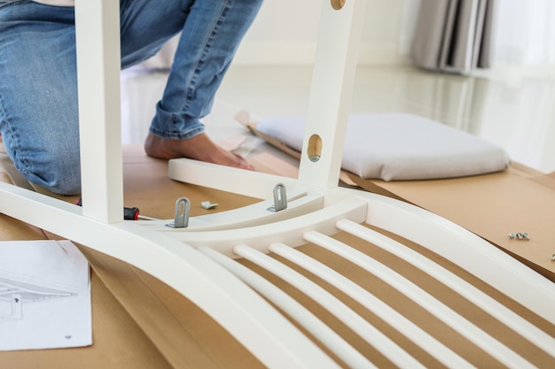 Photo man assembling white chair furniture at home