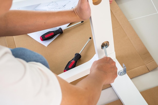 Man assembling white chair furniture at home