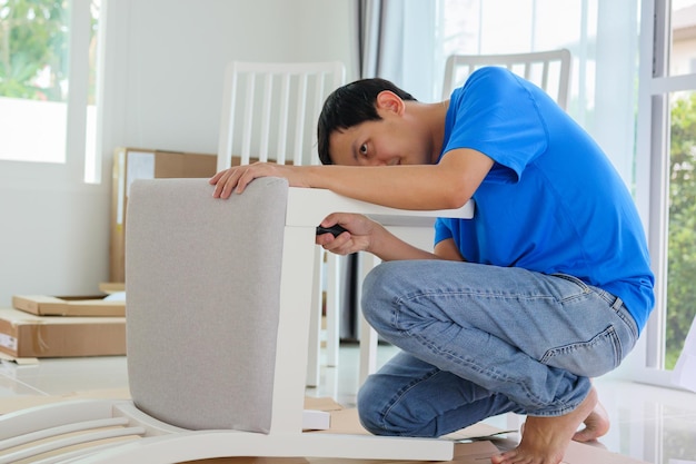 Man assembling white chair furniture at home