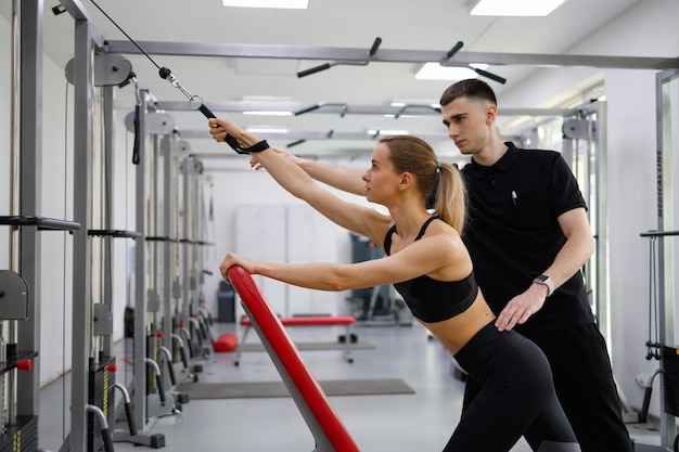 Man assisting woman training in rehabilitation center