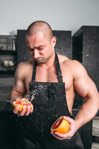 A man an athlete in an apron squeezes a grapefruit