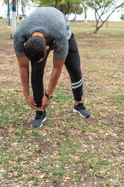 Man athlete tying shoelace in public park