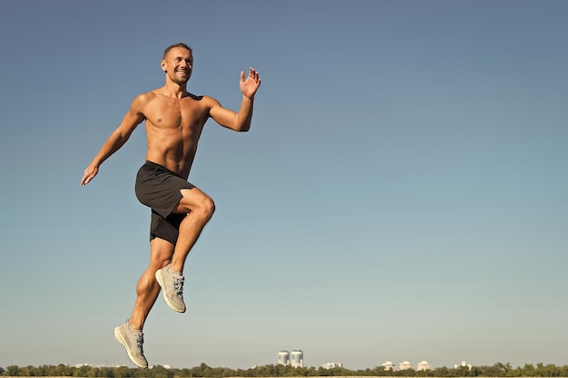 Man atleet gespierde torso lopen Ochtend hardlopen vult met energie Motivatie en prestatie Run ochtend gewoonte Runner beweging vooruit hemelachtergrond Doorsturen naar succes Dagelijkse training voor een gezond leven