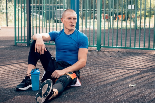 Man atleet zittend op de grond na training buitenshuis