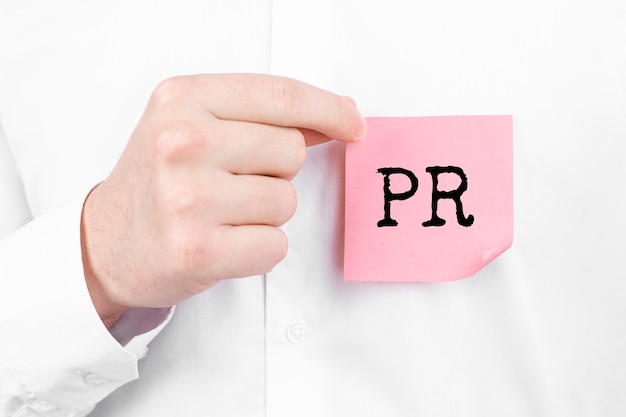 Man attaches a red sticker with text PR overlay to his white shirt