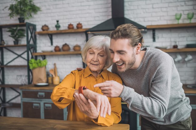 Man attaching smartwatch to his mom hand