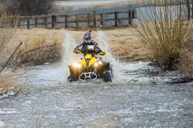 L'uomo sull'atv attraversa un ruscello. il turista cammina su un terreno di fondo.