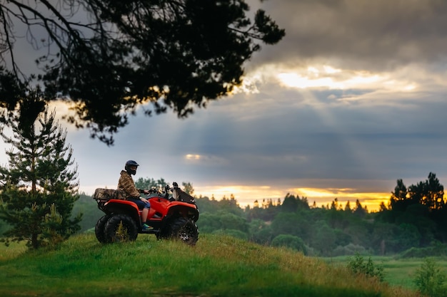 日没で実行されている atv クワッド バイクの男