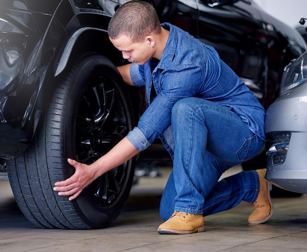 Man automonteur en bandenwissel in onderhoud of service van garagevoertuigen Deskundige professional en reparateur in autowerkplaats of autowinkel die werkt aan reparatie van wielbanden of veiligheidsinspectie