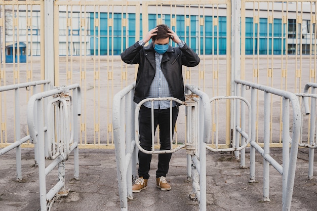 Man on background of fence is holding his hands behind his head