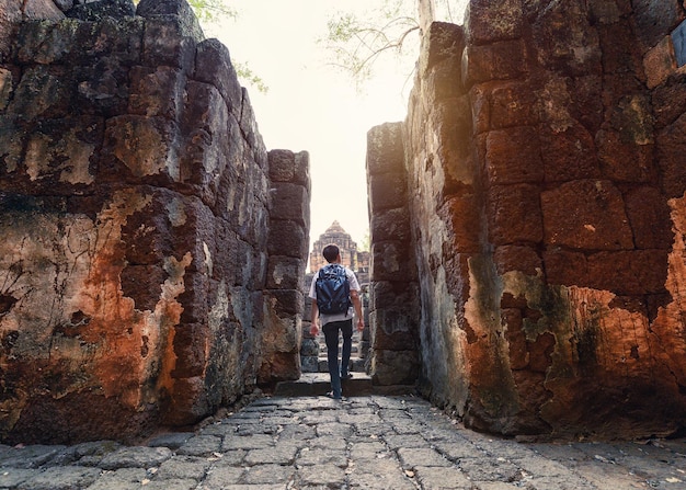 Man backpacker die naar binnen loopt in Prasat Muang Sing zijn oude ruïnes van de Khmer-tempel